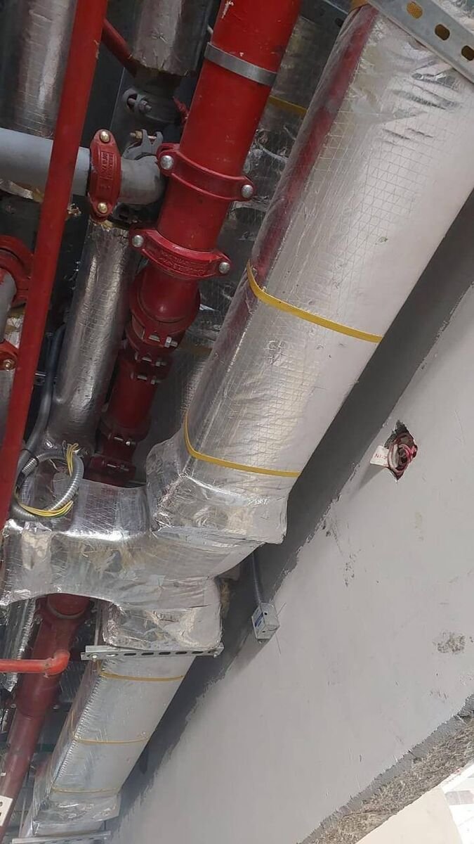 Insulated chilled-water lines run alongside the fire main at ceiling level.