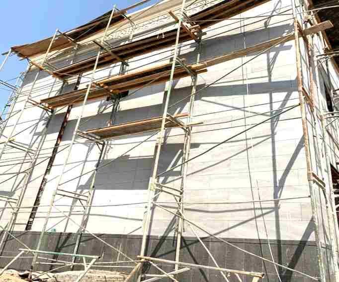 Stone facade panels set from scaffold, floor by floor.