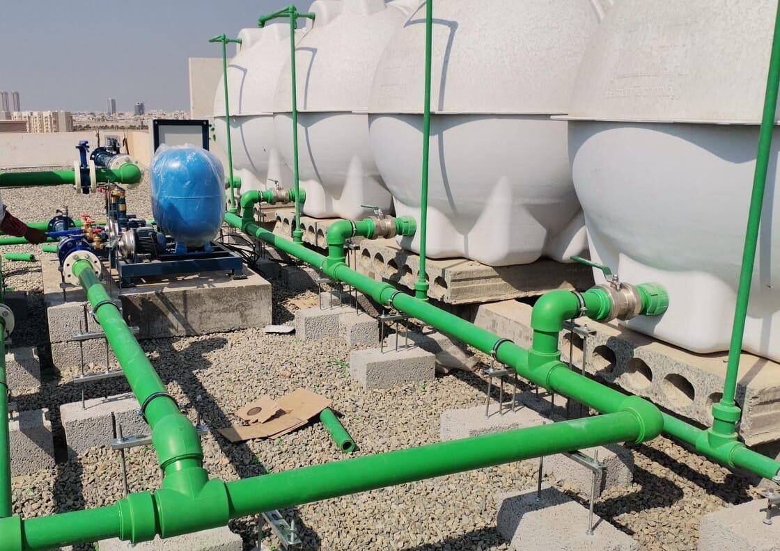 Roof-level water tanks and distribution pipework on plinths.